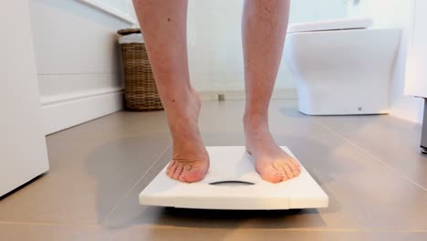 Low-section-of-woman-checking-her-weight-on-weighing-scale-4k