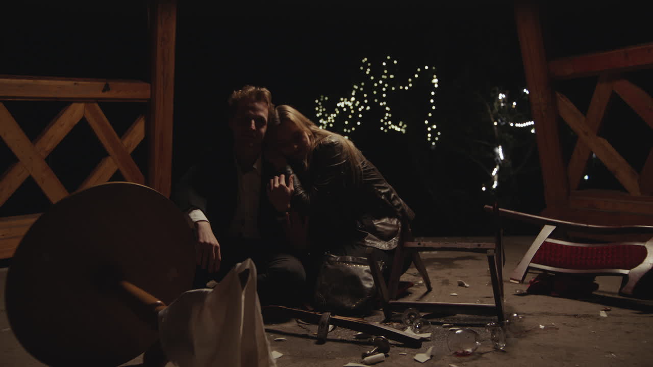A couple sits amidst destruction at night