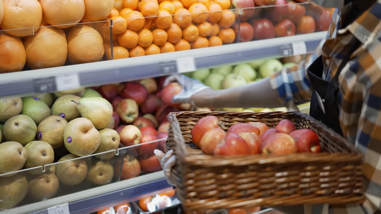 trabajador de supermercado tomando manzanas de los estantes, reorganizando estantes de almacenamiento en el departamento de frutas