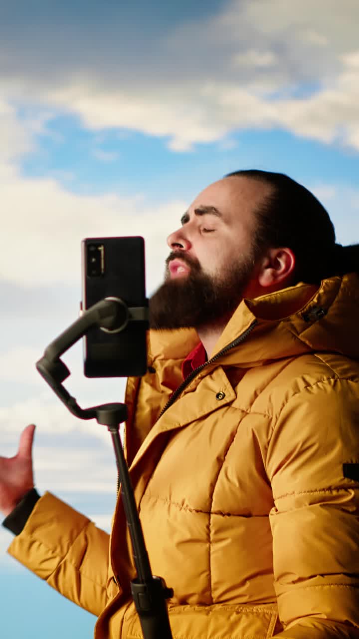 Uomo entusiasta che registra un video verticale con lo smartphone all'aperto