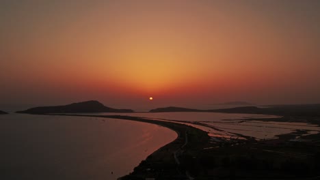 La-Plataforma-Rodante-Inversa-Del-Dron-Desciende-Mientras-La-Bola-De-Sol-Arroja-Un-Brillo-Rojo,-Naranja-Y-Amarillo-En-El-Cielo-Sobre-Pylos,-Grecia