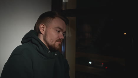 a sad man looking out of a window at night