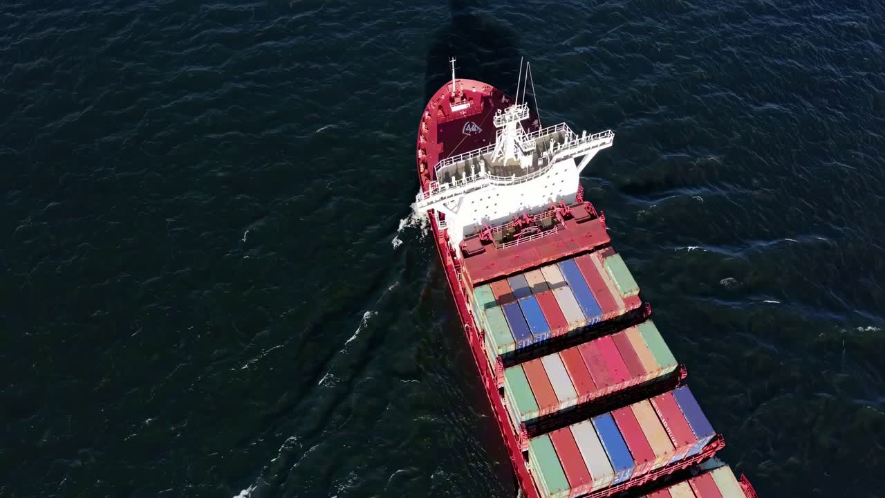 Aerial video of a cargo ship at sea, showcasing a top-down view of colorful containers
