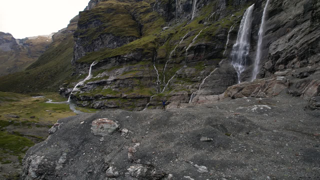 뉴질랜드의 폭포가 있는 탁월한 자연스러운 하이킹 장소에서 승리를 축하하는 사람 - 드론  ⁇ 도