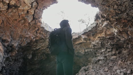 man looking up at massive cave opening at el malpais national monument nm