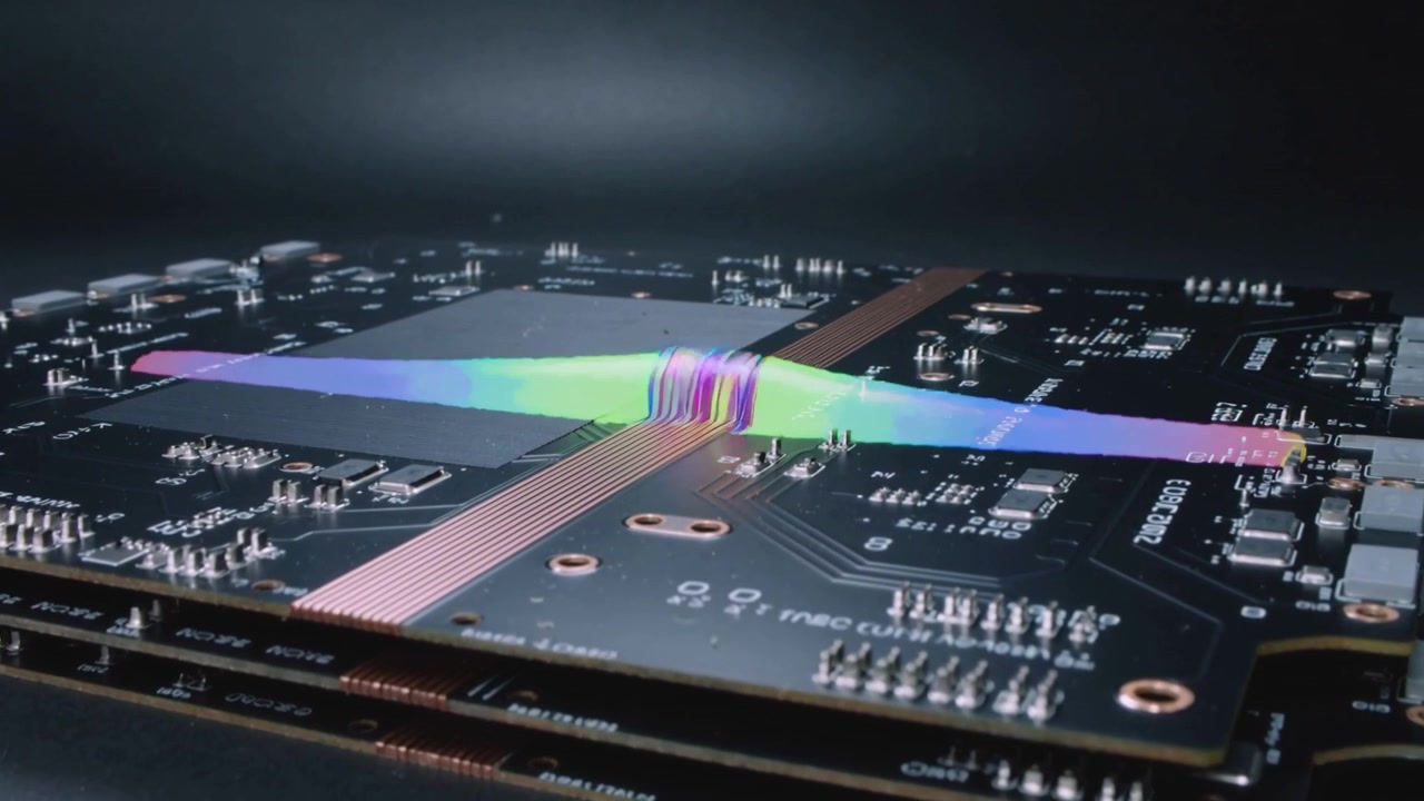 Nastro iridescente che attraversa PCB impilati su un tavolo scuro, avvolgendosi su un pad conduttore in rame