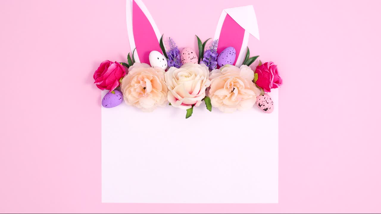 파스텔 분홍색 배경에 종이 카드 노트, 토끼 귀 및 꽃 배열을 가진 부활절 크리에이티브 작곡.