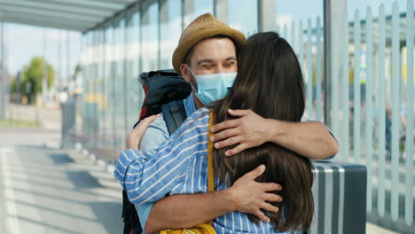 close-up view of happy caucasian young couple meeting at train station and hugging on nice summer day