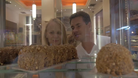 man and woman choosing cakes in confectionery