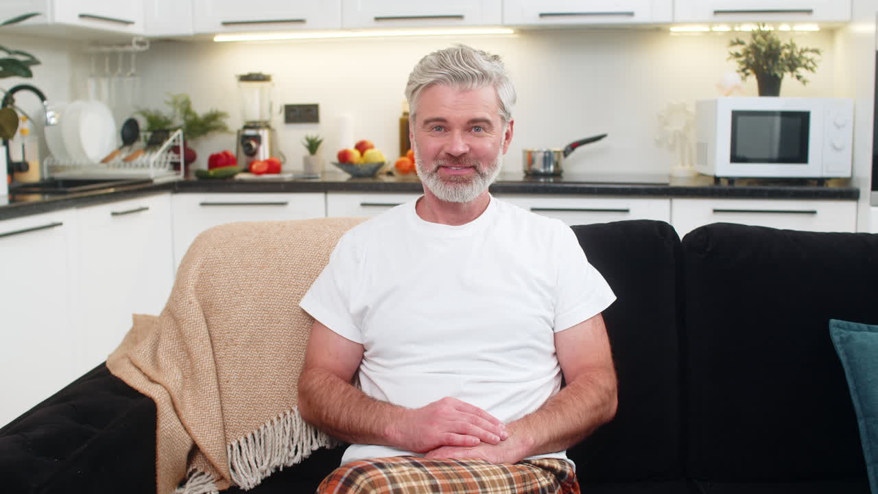Middleaged man waves to camera smiles hello online connection greets viewer friendly positive mood