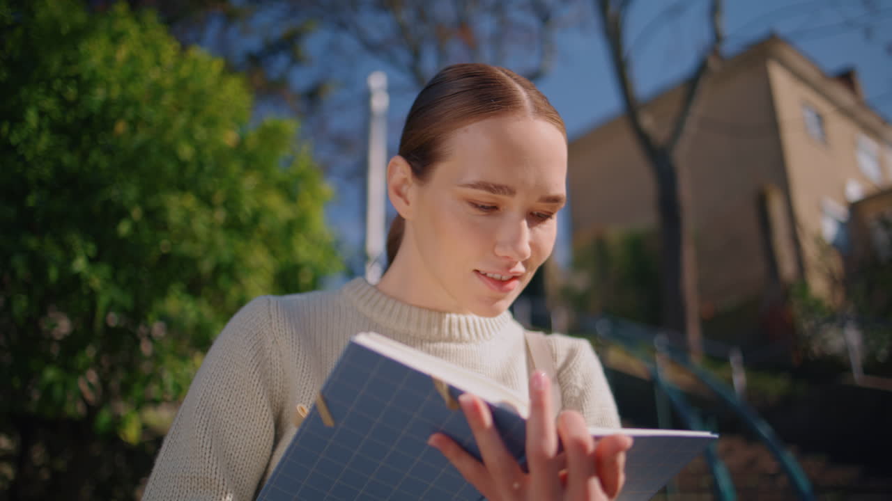 Attractive girl making notes in notebook standing stairs closeup. Woman writing