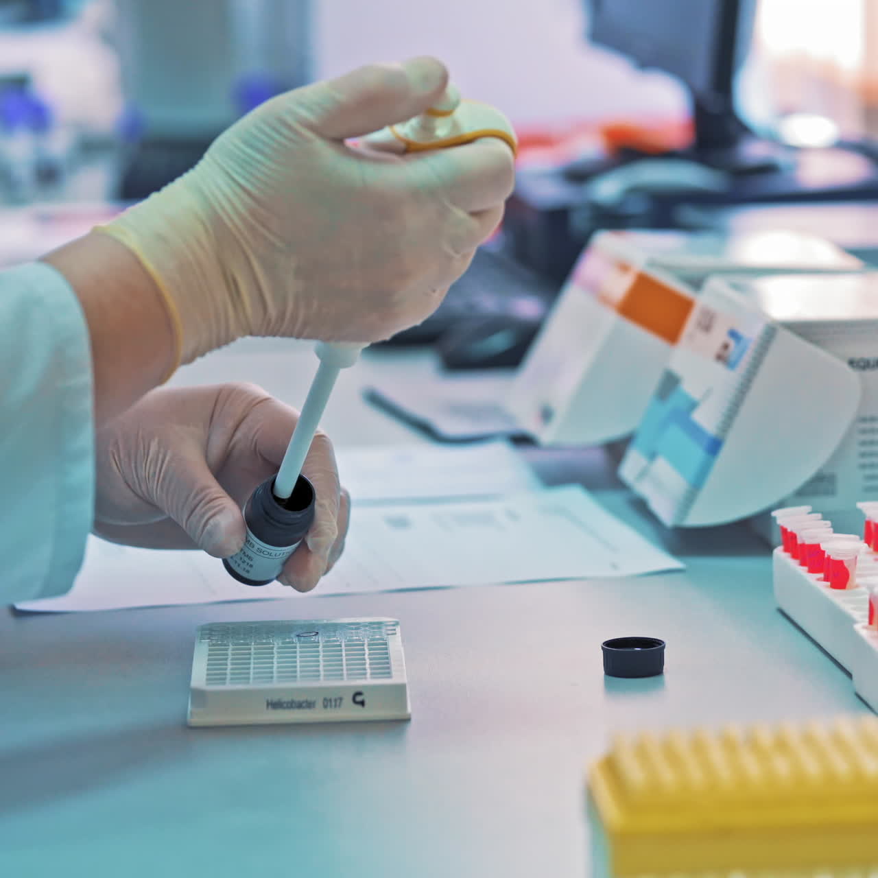Laboratory technician is filling rack with special liquid from the small plastic jar on the table. Medical tests. Clinical diagnostic laboratory equipment.