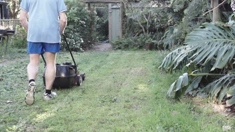 man mowing the lawn in a garden going backwards and forwards hd footage slow motion