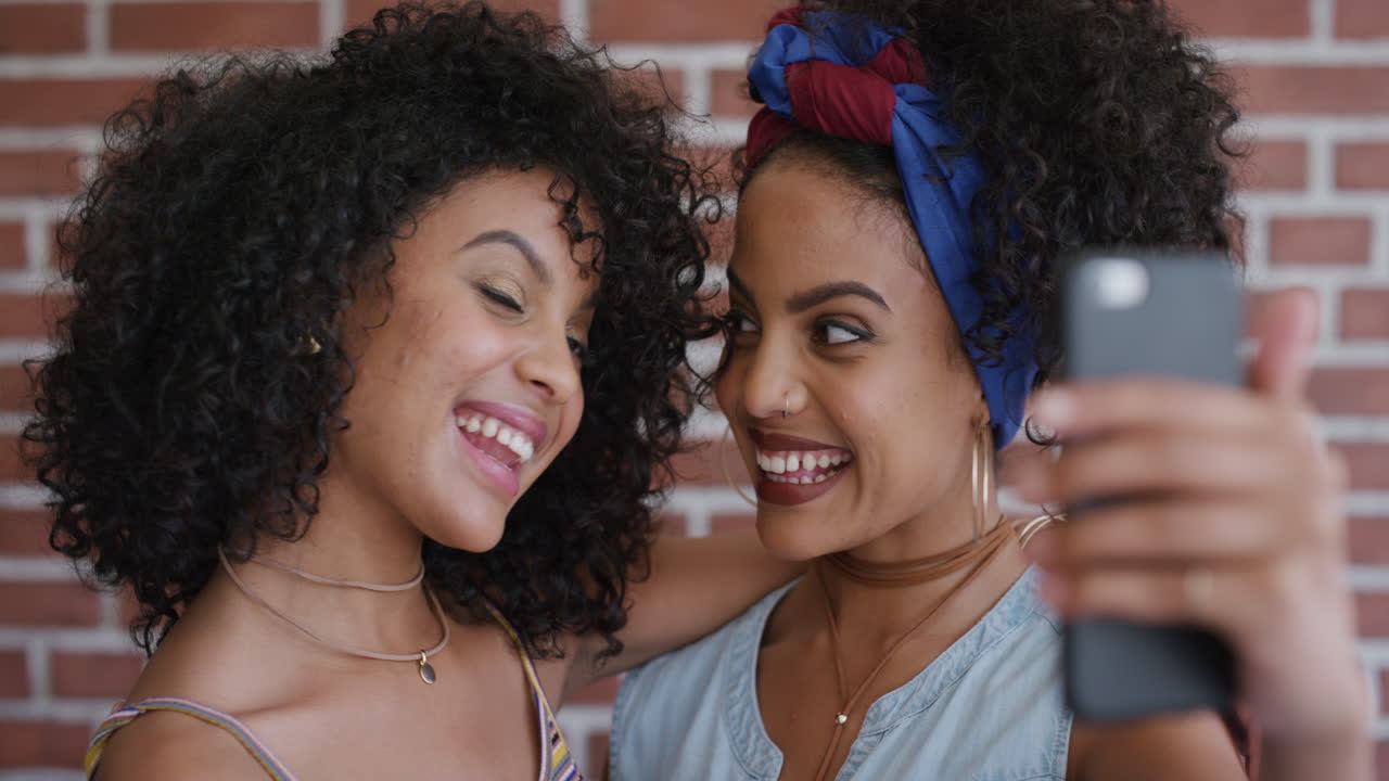 retrato de cerca de hermanas gemelas hispanas atractivas que usan teléfonos inteligentes tomando fotos selfie posando disfrutando de la unión sonriendo felices tecnología de cámara de teléfono móvil