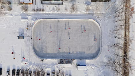 aerial view descending above a ice hockey game at a outdoor rink, winter day