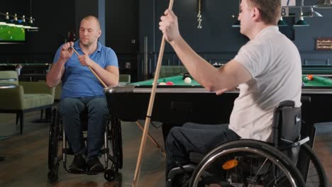 adult men with disabilities in a wheelchair play billiards in the club