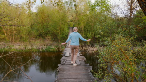 woman walking across a wooden bridge in a forest