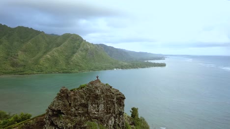 Drone-shot-circling-a-pair-of-hikers-standing-on-top-of-the-cliffs-on-the-Crouching-Lion-hike-on-Oahu,-Hawaii