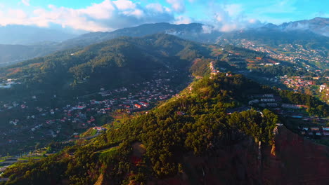 mountains with lush greenery and lots of houses. thick cloudscape floating above the rocks. panorama of the madeira islands, portugal from top.