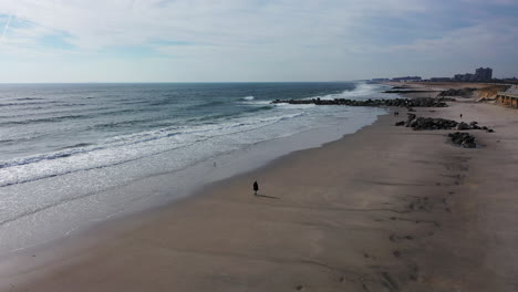 Una-Vista-De-Drones-Sobre-Una-Playa-Tranquila-Con-Una-Persona-Caminando-Por-La-Mañana