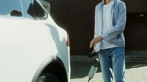 man charging electric vehicle at home