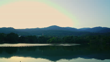 timelapse ang kaew lake at chiang mai university with forested mountain and twilight sky