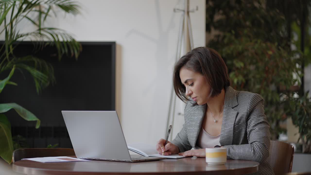 Mujer trabajando desde casa usando una computadora portátil mientras lee un mensaje de texto. Mujer usando laptop para trabajar o estudiar en la oficina. Empresaria tecleando en la laptop en el lugar de trabajo. Mujer trabajando en la oficina en casa con la mano en el teclado.