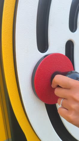 close-up of a hand interacting with a red and black element on an abstract outdoor display