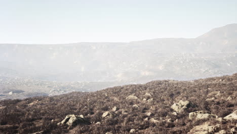 a view of a misty mountain range with rocky terrain