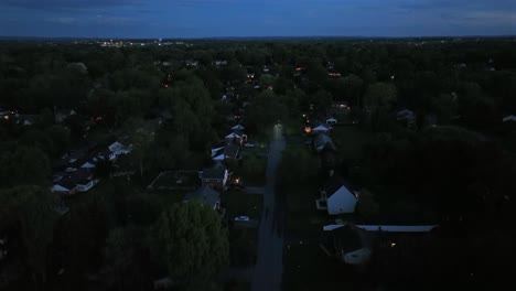 single family houses at night. twilight aerial view of a quiet suburban street with two-story houses. green trees on spring day in may. aerial rising wide shot. quiet neighborhood scene.