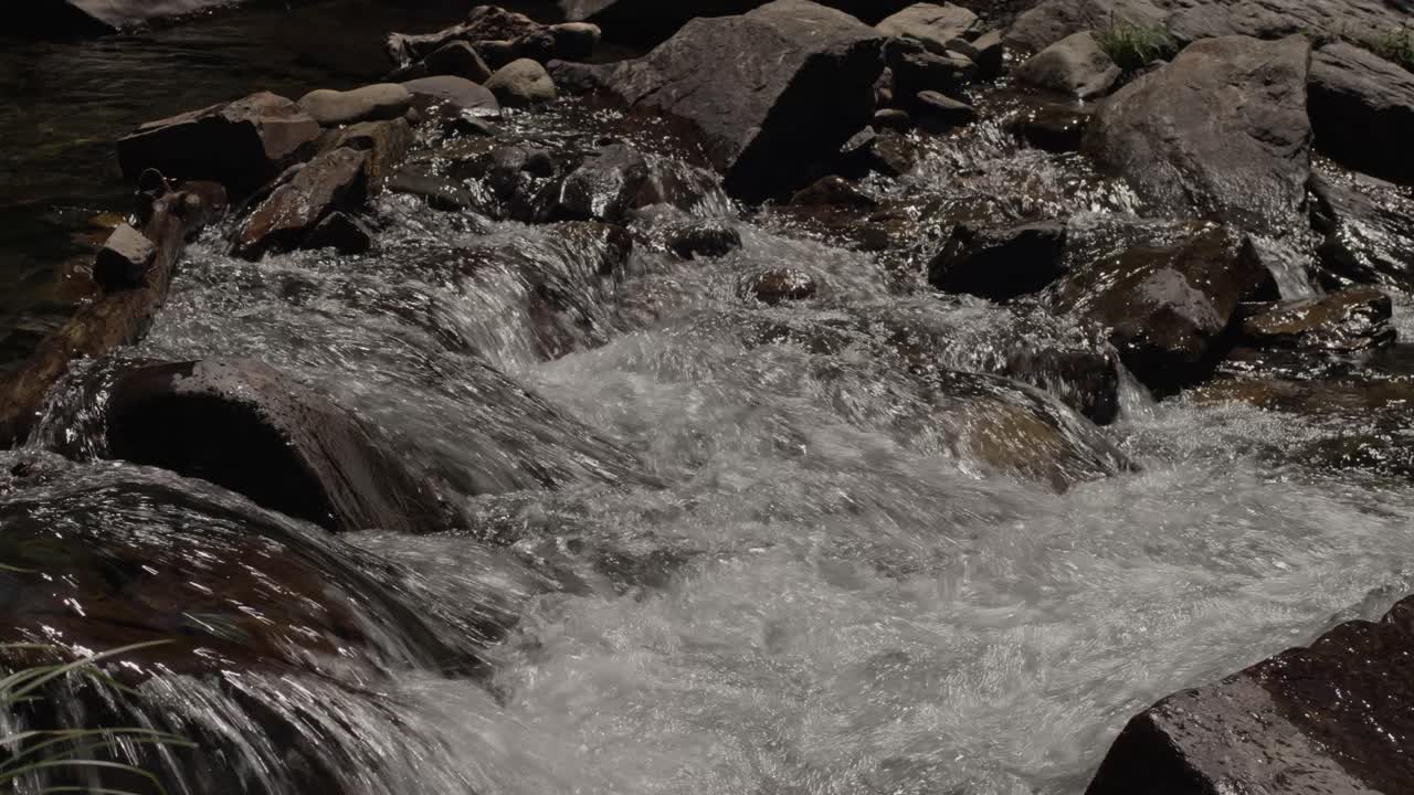 Acqua di torrente che scorre su rocce e pietre in un ambiente naturale.