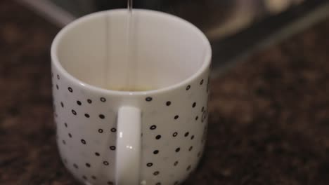 slowly pouring hot water in a cup with soup mix - close up shot