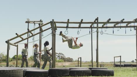 Fit-diverse-group-of-soldiers-using-hanging-rope-and-rings-on-army-obstacle-course-in-the-sun