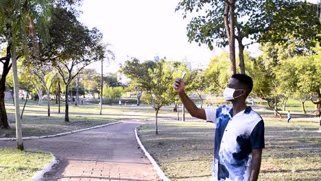 alone young man doing selfie in the square with corona prevention facial mask