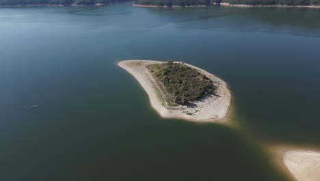 imágenes aéreas de una pequeña isla aislada rodeada de aguas tranquilas en un vasto embalse