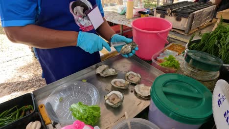 person shucking and garnishing oysters outdoors.