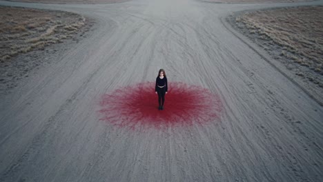 young woman standing on a red stain resembling blood at a crossroad, evoking a sense of mystery and drama while contemplating choices and the uncertainty of her future