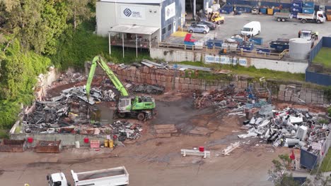 drone footage captures a busy junkyard with machinery sorting metal under bright daylight in gold coast, australia