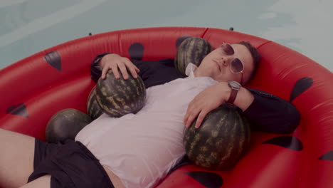 man relaxing in a watermelon-shaped pool float