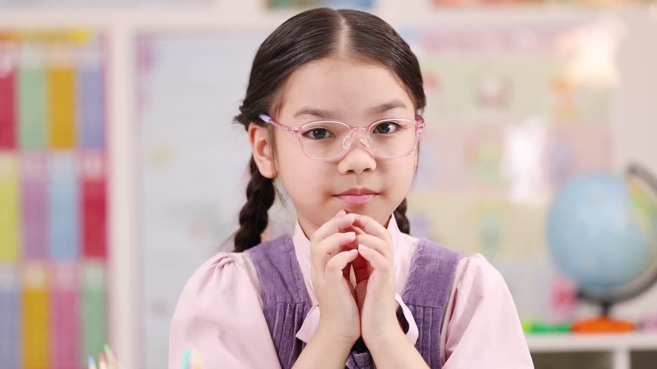 Young girl with glasses shows surprise and curiosity in bright, colorful classroom environment