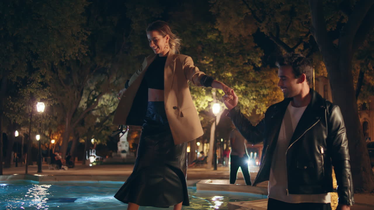 Affectionate sweethearts enjoying time together at night. Happy girl stepping