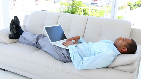 businessman falling asleep on the sofa with laptop