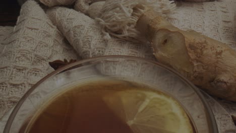 Hot-cup-of-tea-with-lemon,-ginger-and-cinnamon-sticks-on-wool-cloth,-dolly-backward