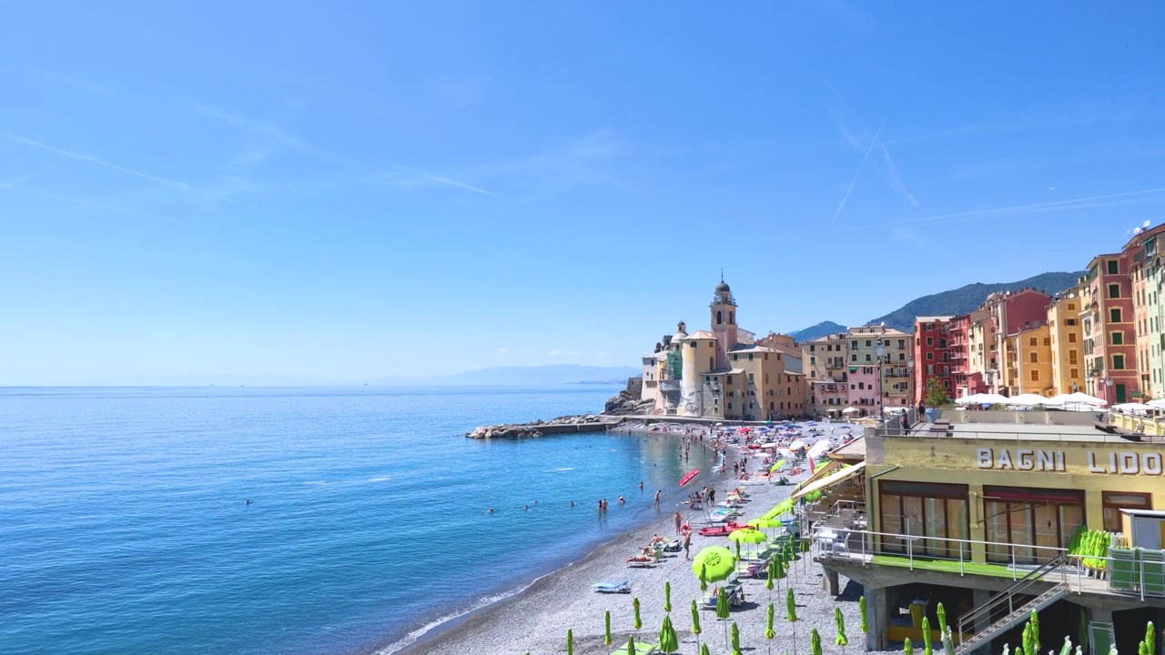 Una lenta panoramica della telecamera rivela la colorata architettura marittima e una spiaggia soleggiata a Camogli.