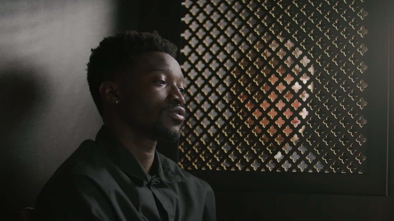 African American Man Confessing to Priest in Dimly Lit Booth