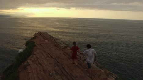 loving couple kissing on rocky cliff near sea