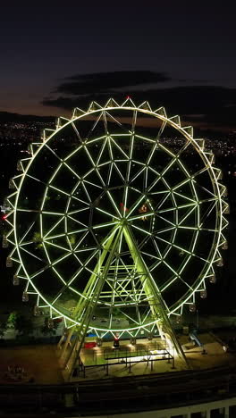 vertical drone shot orbiting the ferris wheel of aztlan park, night in cmdx
