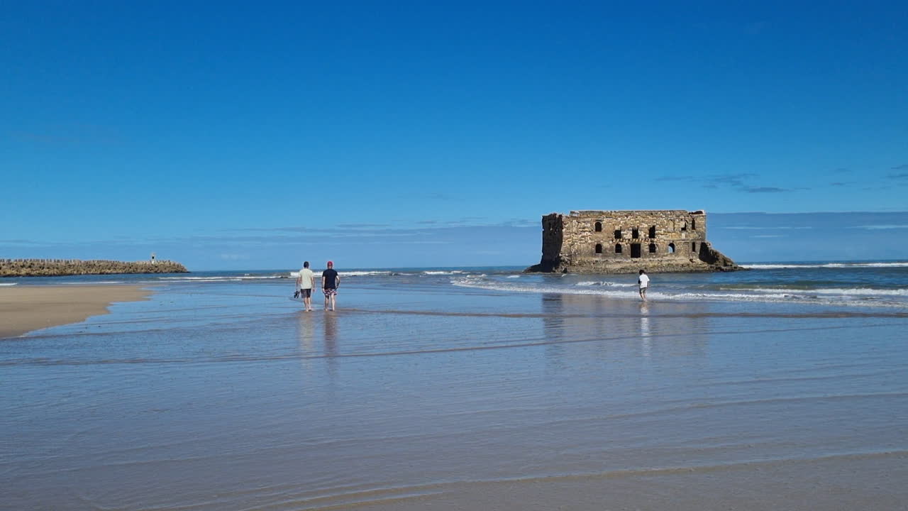 three people walking towards the beach in Casa del mar, Tarfaya, Marroco. 4K videos. walk along the sandy beach