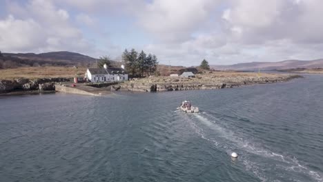 Aerial-shot-tracking-a-small-boat-arriving-at-the-slipway-on-the-inner-Hebridean-island-of-Ulva,-on-an-overcast-day