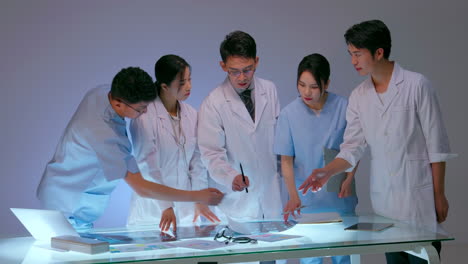 Young expert doctor holding clipboard explaining diagnosis of patient in front of medicine experts during seminar. Clinic therapist talking with colleagues about disease, medicine healthcare